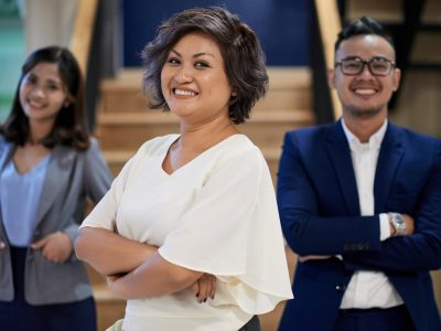 Cheerful pretty Asian business woman standing in from of her employees